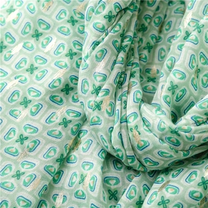 Detail of mint green scarf featuring geometric clover print and gold foil stamping texture