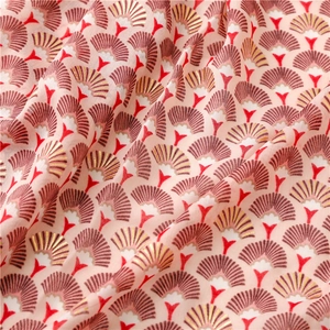 Gros plan détaillé des motifs d'éventail dorés et floraux sur cette écharpe en coton doux