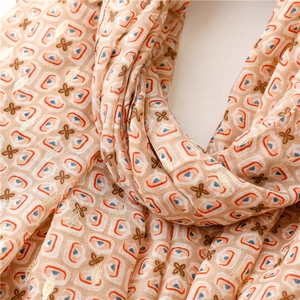 Detail of soft orange scarf showing geometric prints and gold floral foil accents