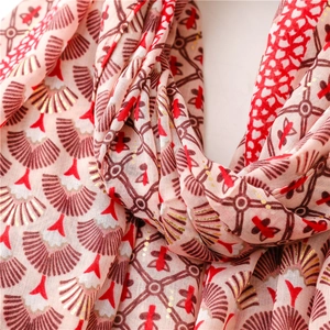 Détail d'une écharpe rose avec motifs d'éventails dorés et imprimés floraux fins