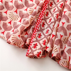 Détail de l'écharpe en lin avec motifs d'éventails dorés et imprimés végétaux sur tissu rose