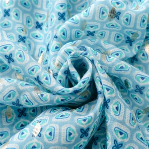 Macro detail of sky blue scarf with geometric prints and shimmering silver metallic thread