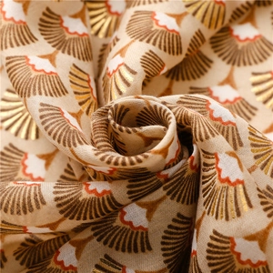 Gros plan sur l'écharpe en coton lin avec motifs éventail dorés et fleurs orangées