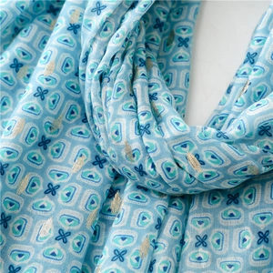 Close-up of light blue cotton-linen scarf with geometric patterns and gold foil detail