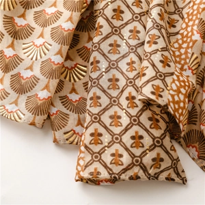 Détail des motifs floraux en éventail et dorure à l'or sur un tissu écharpe lin