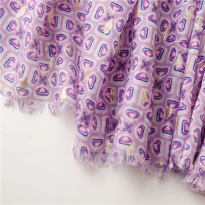 Macro detail of purple geometric floral print scarf with gold foil accents and fringe edges