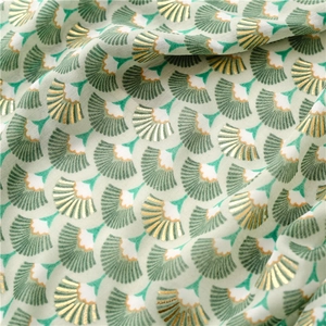Détail d'une écharpe verte à motifs d'éventails avec dorures élégantes et tissu souple
