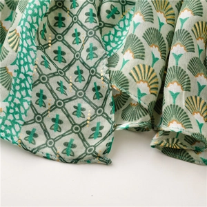 Détail d'écharpe en lin vert avec motifs éventail dorés et bords ourlés fins