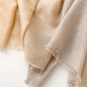 Detail of gradient cotton scarf with metallic gold foil texture and soft fringed edges