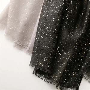 Close-up of metallic gold foil dot patterns on soft gray and black cotton-linen scarves