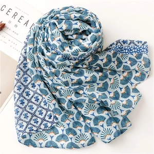 Détail d'écharpe en lin bleu clair avec motifs d'éventails dorés et bordure géométrique