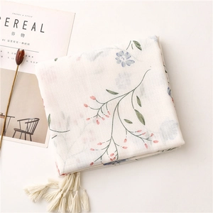 Dettaglio sciarpa in cotone bianco con stampa floreale blu e nappine fatte a mano