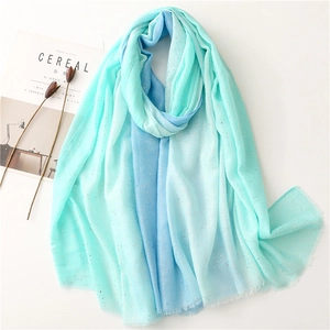Detail of mint green gradient scarf with golden glitter accents and fringe edges