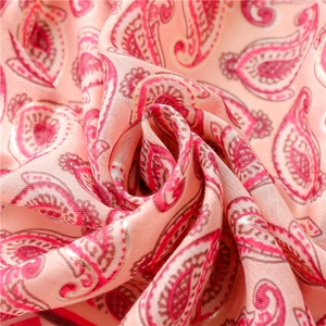 Detail of pink paisley scarf with intricate gold metallic threads and soft fabric texture