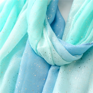 Detail of blue-green gradient scarf featuring sparkling gold glitter and soft texture