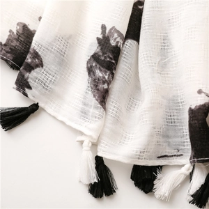 Close-up of elegant cotton linen scarf featuring hand-painted black prints and tassels