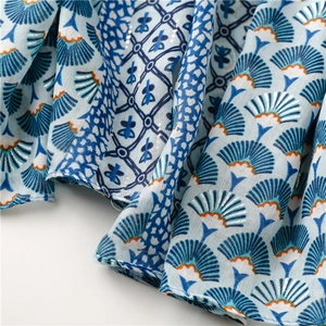 Détail d'une écharpe bleu clair aspect lin avec motifs d'éventails argentés et fleurs