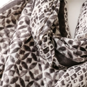 Close-up of lightweight satin scarf featuring geometric rhombic and leopard print patterns