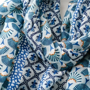 Détail d'écharpe bleue avec motif d'éventail et bordure orange sur tissu lin doux