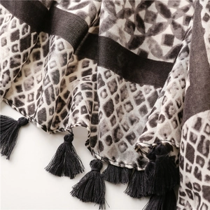 Macro detail of scarf featuring snake print, geometric patterns, and black fringe edges