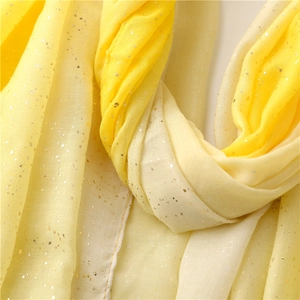Detail view of yellow gradient shawl with shimmering gold glitter and soft texture
