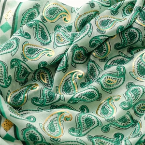 Detail of mint green paisley scarf with golden foil printing and soft linen-feel texture