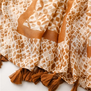 Detail of geometric plaid cotton scarf with fine brown fringe tassels and soft fabric