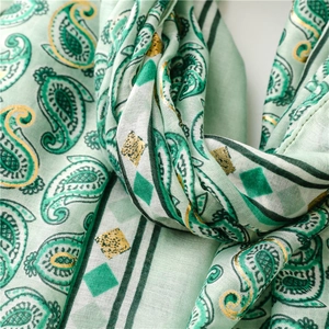 Detailed macro shot of mint green paisley scarf with shimmering gold foil accents