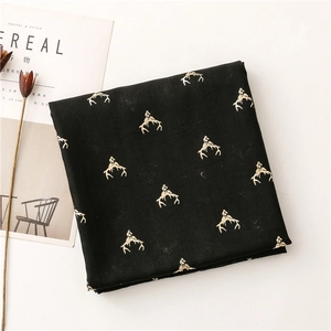 Detail of black scarf featuring golden reindeer antlers print next to a magazine