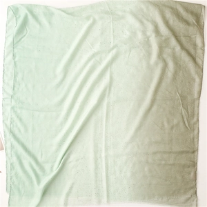 Detailed texture of mint green gradient scarf with shimmering silver sequins and frayed edges