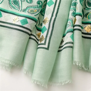 Detailed macro of light green paisley linen scarf with gold foil accents and fringe