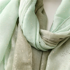 Close-up of mint green shawl featuring delicate gold glitter print and elegant fabric drape