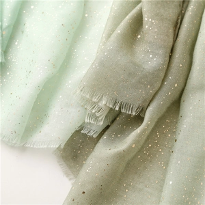 Close-up of mint and dust pink scarves with elegant gold foil specks and frayed edges