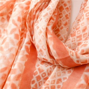Detail of soft linen-touch satin scarf showing geometric orange diamond and snake patterns