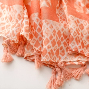 Close-up of lightweight orange and white geometric pattern scarf with soft fringe tassels
