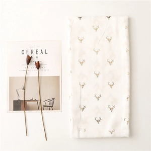 Detail of soft white scarf featuring golden reindeer patterns and decorative magazine setup