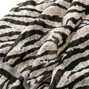 Macro view of leopard and zebra print scarf with silver foil details on cotton linen fabric