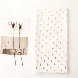 Detail of white scarf featuring gold and silver foil diamond pattern with fringe edges