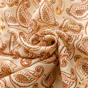 Close-up of paisley print on lightweight cotton-linen scarf with golden foil accents