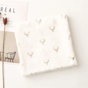 Close-up of lightweight white scarf featuring elegant gold deer head foil patterns