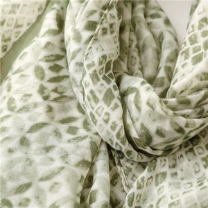 Detailed macro view of soft kaleidoscope pattern silk scarf with geometric green print