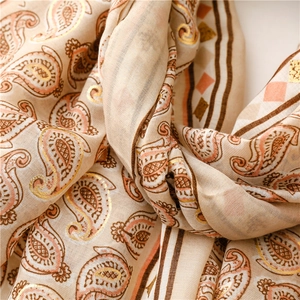 Detailed macro view of beige cotton linen scarf with paisley prints and gold foil accents