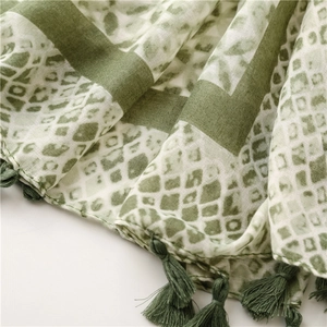 Detail of green and white geometric scarf fabric with delicate handmade tassels