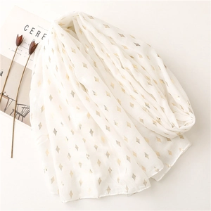 Close-up of white scarf featuring elegant gold foil diamond patterns and soft texture