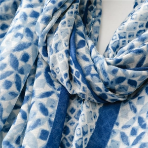 Detailed close-up of a blue and white geometric kaleidoscope pattern silk scarf with soft texture