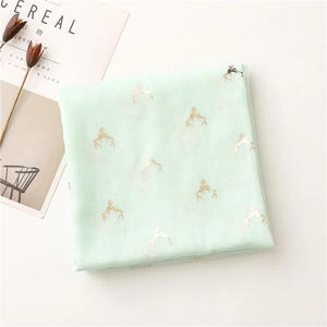 Close-up of mint green scarf with gold foil reindeer patterns and soft texture