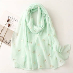 Detail of mint green scarf featuring golden deer prints and soft roll-edge texture