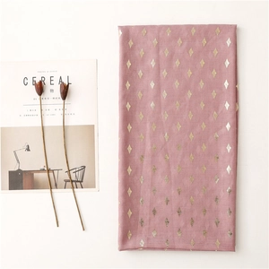 Detail of pink cotton-linen scarf with gold diamond foil pattern and dried flowers