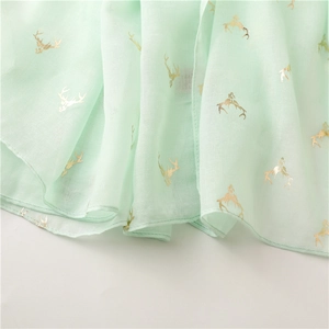 Detail of mint green fabric with metallic gold deer prints and soft textured finish