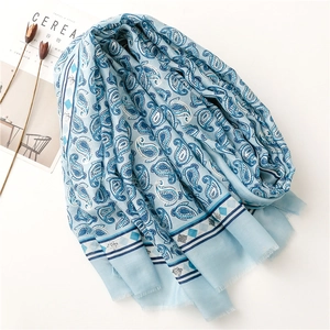 Detailed macro view of light blue paisley cotton scarf with silver foil prints and tassels